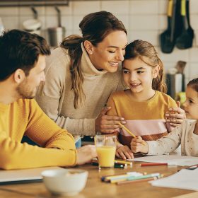 happy-parents-enjoying-with-their-small-daughters-who-are-coloring-paper-home