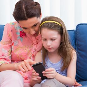 mother-daughter-using-smartphone-couch