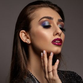 woman-black-shiny-dress-is-touching-her-face-posing-gray-background-luxury-makeup-colorful-eye
